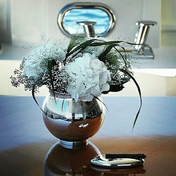 Silver vase with flowers on a reflective surface