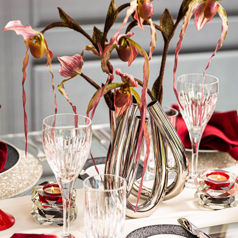 Decorative table setting with silver vase, pink flowers, and crystal glasses.