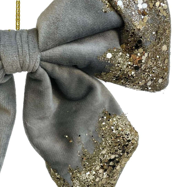 Close-up Gray velvet bow with gold glitter by Shishi, used as a hanging Christmas ornament or elegant napkin decoration.