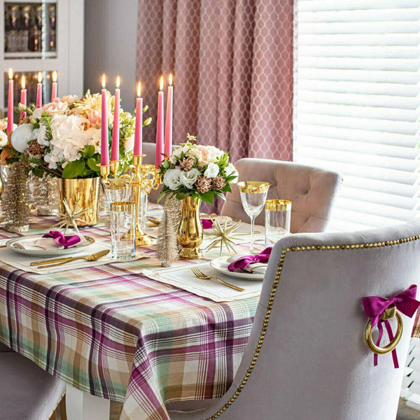 Dining table set with floral centerpieces, candles, and plaid tablecloth.