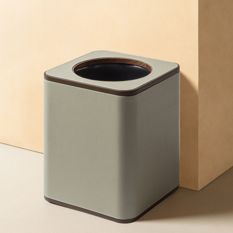 Luxury leather wastepaper bin by Giobagnara x Poltrona Frau with Pelle Frau leather, removable lid and inner container on a beige background