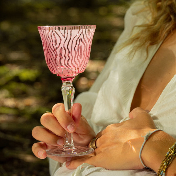 Woman holding an elegant pink crystal water glass featuring dreamlike woodland design, Alice Collection