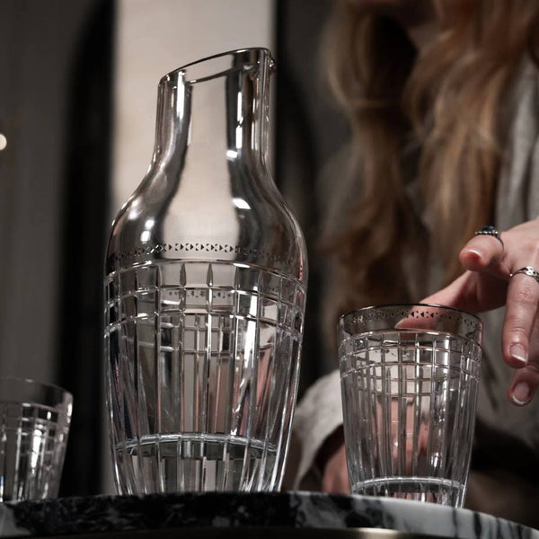 Crystal carafe and glass on a table with a blurred person in the background