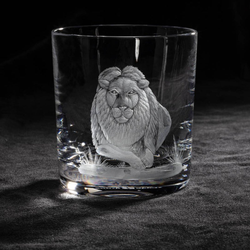 Clear glass tumbler with a engraved lion design on a dark background