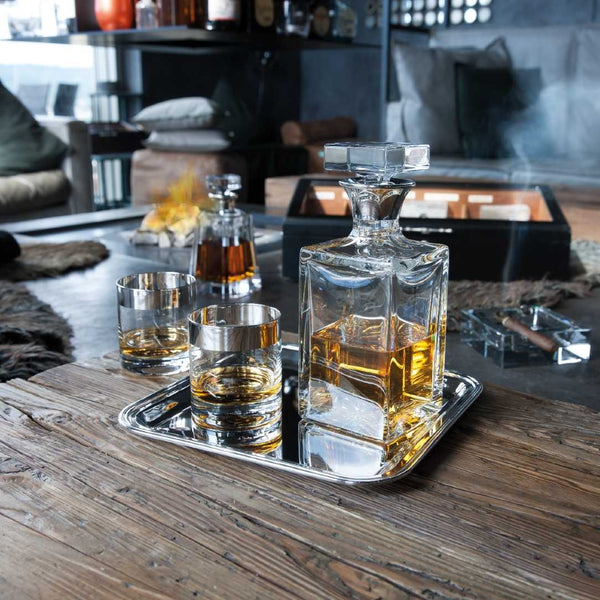 Glass whiskey decanter and Whisky Glass Crystal with 2cm Fine Silver Rim – Paris Collection by Sonja Quandt on a tray with a cozy indoor setting.
