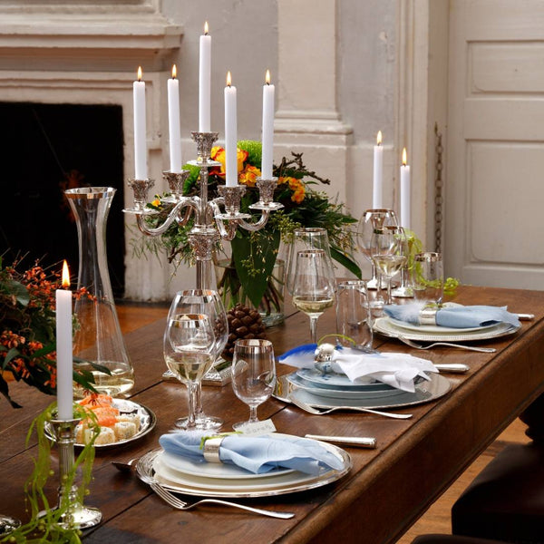 Elegant dinner table setting with candles, handcrafted White Wine Glasses in Crystal with Fine Silver Decor – Avantgarde Collection Sonja Quandt, and flowers in a formal room.