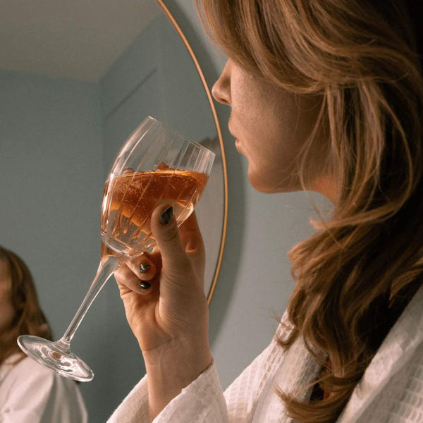 Woman holding a glass of Saint-Rémi crystal white wine glass with fine bevel cuts by Cristallerie de Montbronn.