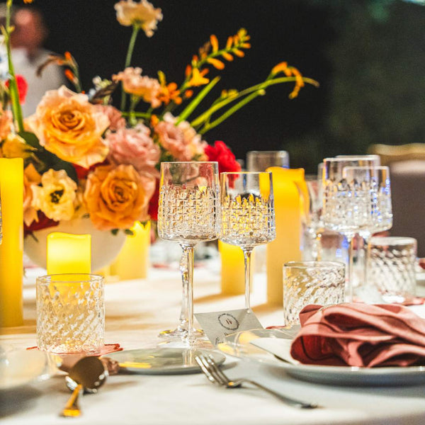 Decorative table setting with flowers, candles, and glasses Ulysse white wine glass in luxury French crystal with hand-cut siren-scale motifs.