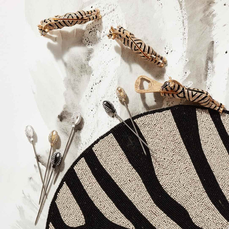 Decorative items including a zebra-patterned place card holder and a bottle opener on a textured surface.
