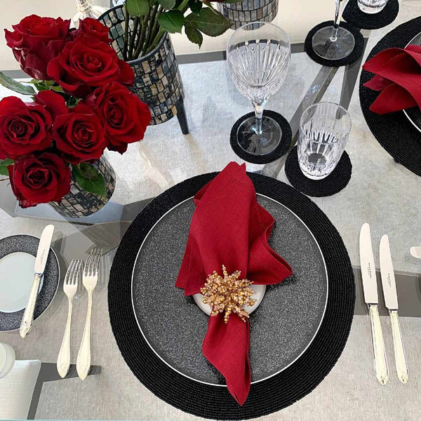 Elegant table setting with red roses, black plates, and red napkins.