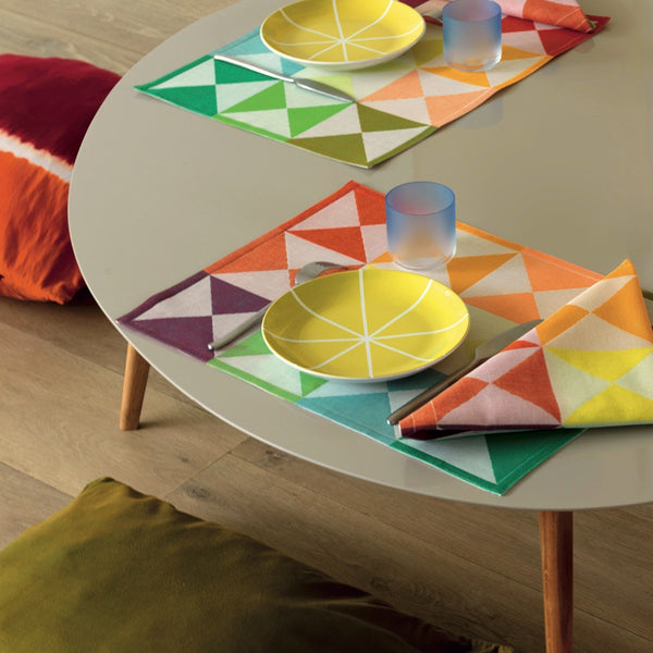 Multicolored reversible cotton placemat with geometric pattern on coffee table.