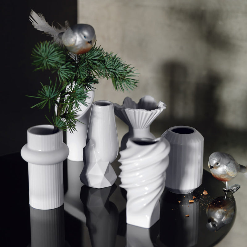 a group of white vases and a plant on a table
