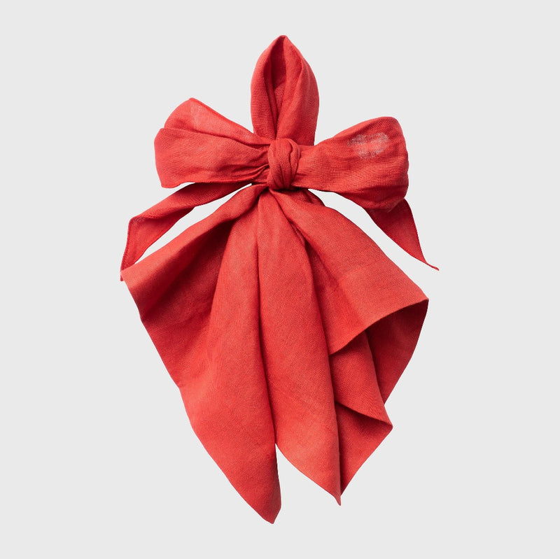 Pre-tied red linen napkin in a bow shape on white background, sold at Amiramour.