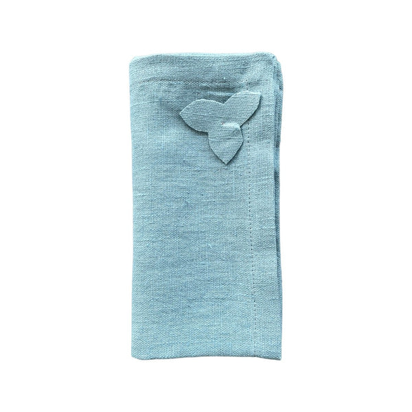 Sky blue linen napkin with hydrangea appliqué, folded neatly on white background, sold at Amiramour.