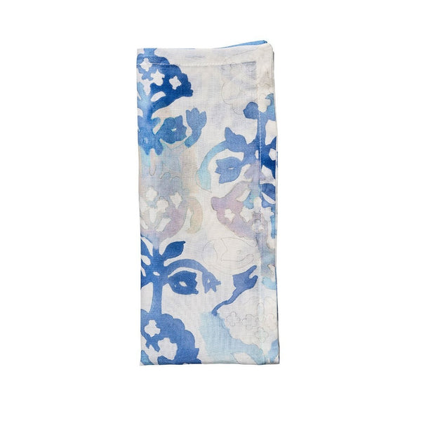 Watercolour linen napkin in white with blue, pink, and purple floral design folded on white background, sold at Amiramour.