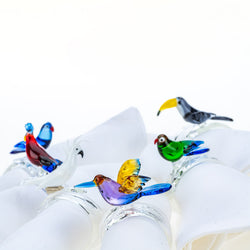 Handcrafted tropical birds napkin rings by Casa Rialto styled on white linen napkins close-up.