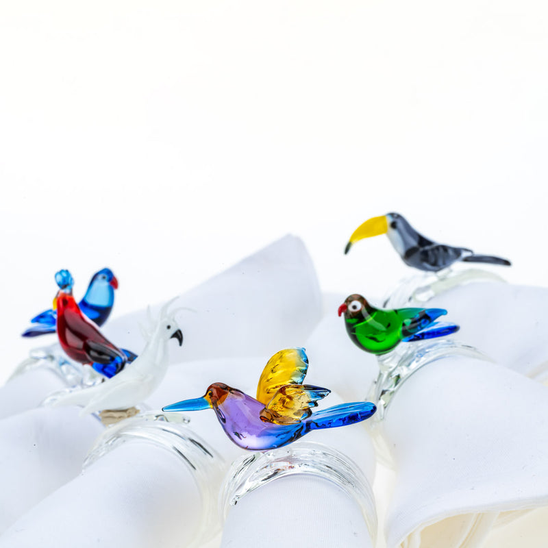 Handcrafted tropical birds napkin rings by Casa Rialto styled on white linen napkins close-up.