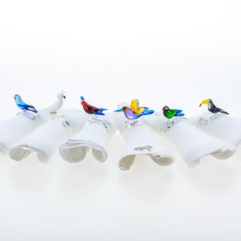 Handcrafted tropical birds napkin rings by Casa Rialto styled on white linen napkins.
