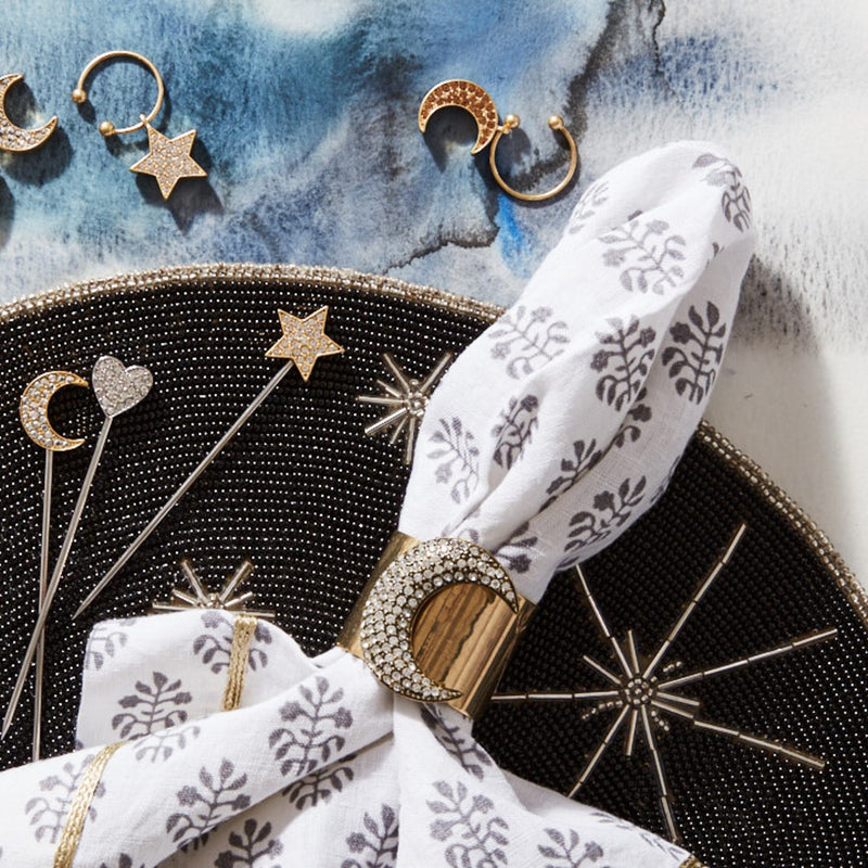 Amiramour Moon napkin ring in brass gold, styled on a beaded placemat.