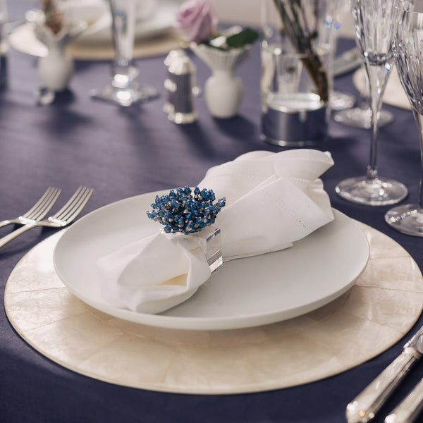 Natural Capiz shell round placemat with  by Kim Seybert styled with sparkle blue napkin ring.