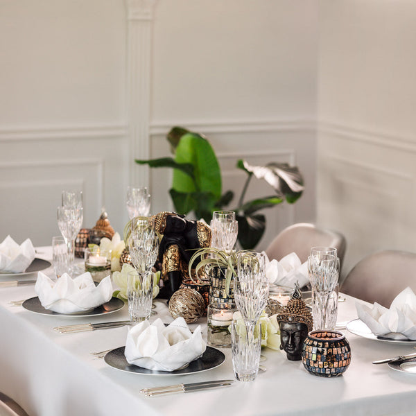 Elegant dining table styled with the Simply Asia themed décor set from Amiramour, showcasing Buddhas, mosaic glass vases, and white floral details.