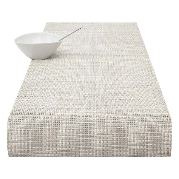 A natural-colored basketweave table runner with a textured surface, displayed on a white background alongside a white bowl for scale.