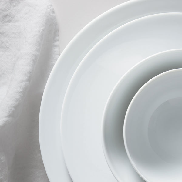 4 white plates different sizes on a white tablecloth