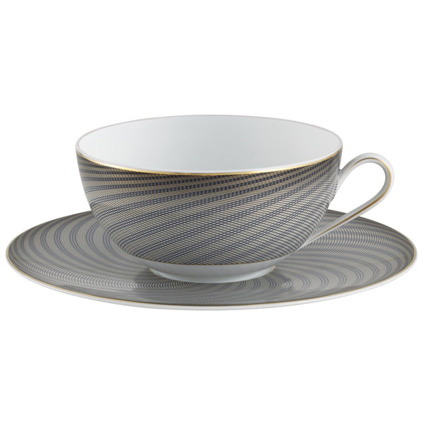 A white porcelain breakfast cup with black and gold geometric patterns on the cup and saucer, held by a gold-colored handle.
