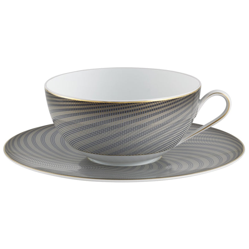 A white porcelain breakfast cup with black and gold geometric patterns on the cup and saucer, held by a gold-colored handle.