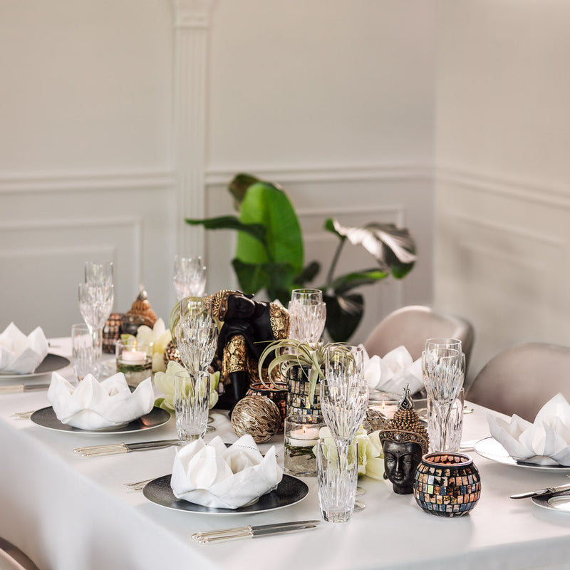 asian style table decor featuring Buddha head statue with gold and black colour, black and white plates and crystal glasses