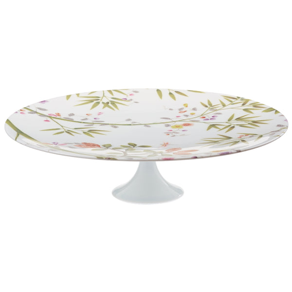 A white porcelain cake stand with a floral pattern and green accents, featuring birds and paradise-themed motifs.