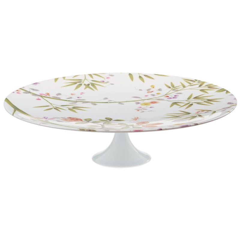 A white porcelain cake stand with a floral pattern and green accents, featuring birds and paradise-themed motifs.