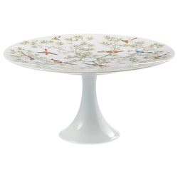 A white porcelain cake stand with a floral and animal pattern, featuring birds and lush greenery motifs.