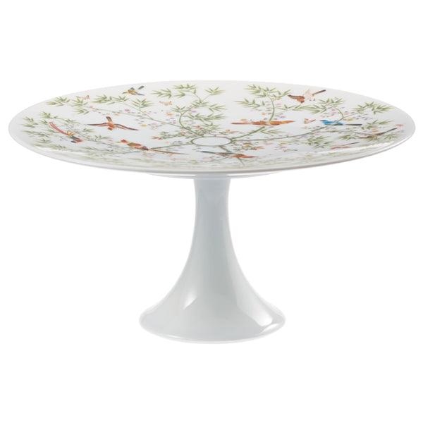 A white porcelain cake stand with a floral and animal pattern, featuring birds and lush greenery motifs.