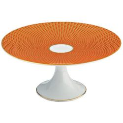 A round orange porcelain cake stand with a geometric honeycomb pattern and gold accents, complemented by a white base.