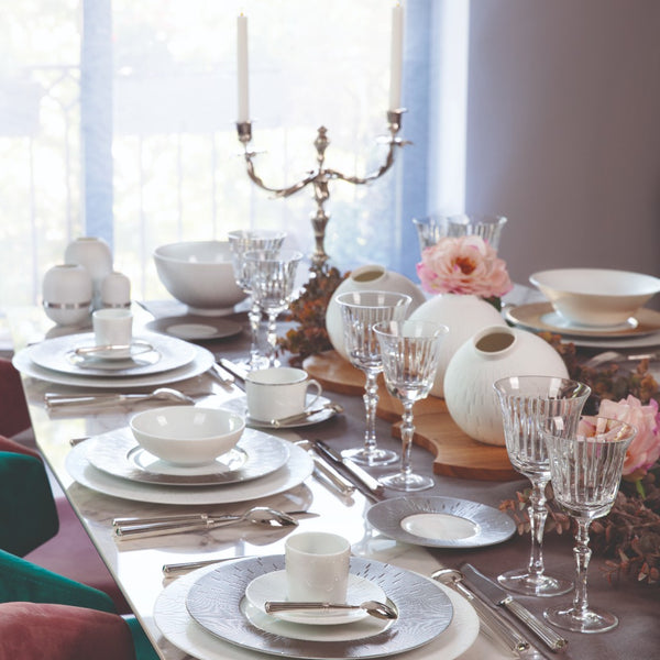 table decorated with white porcelain plates and bowls featuring decoration like vases and flowers