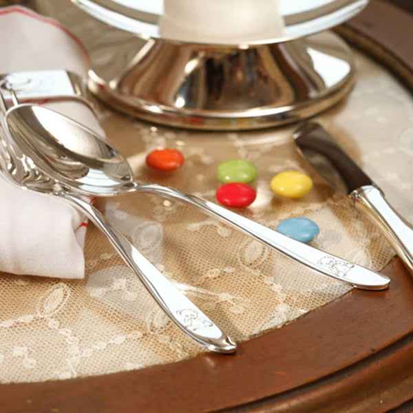 Styled table with Silver-plated 3-piece children’s cutlery set with engraved teddy bear motif by Sonja Quandt.