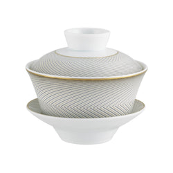 A Raynaud porcelain tea set with black and gold geometric patterns on a white background, including a taller cup and a shorter bowl.