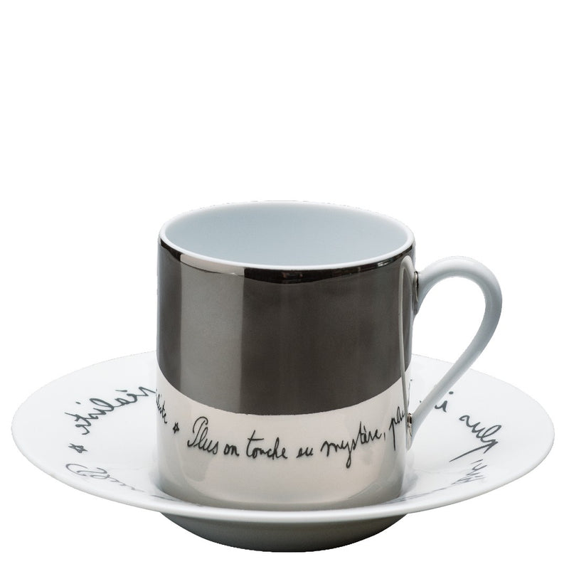 A Raynaud branded coffee cup with a saucer Béatrice featuring a mirrored platinum finish and a quote in French from Jean Cocteau on the saucer.