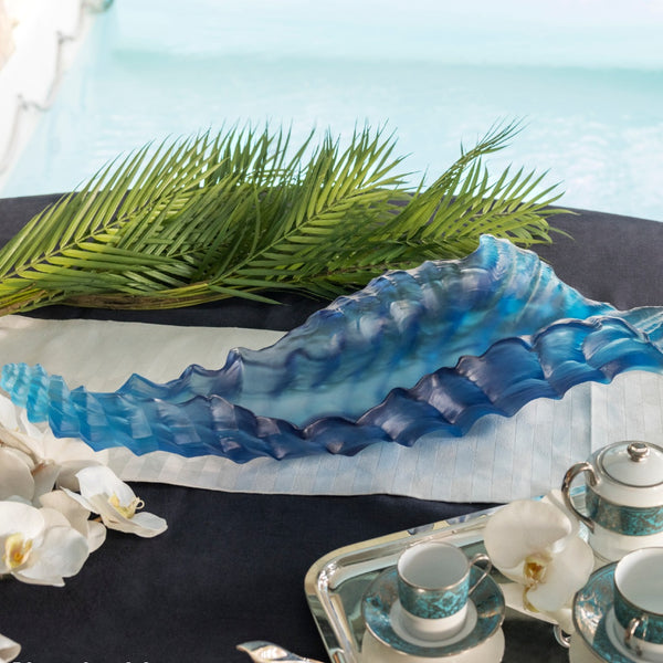 A blue crystal centerpiece sculpture with a wavy, coral-like pattern on a black coffee table