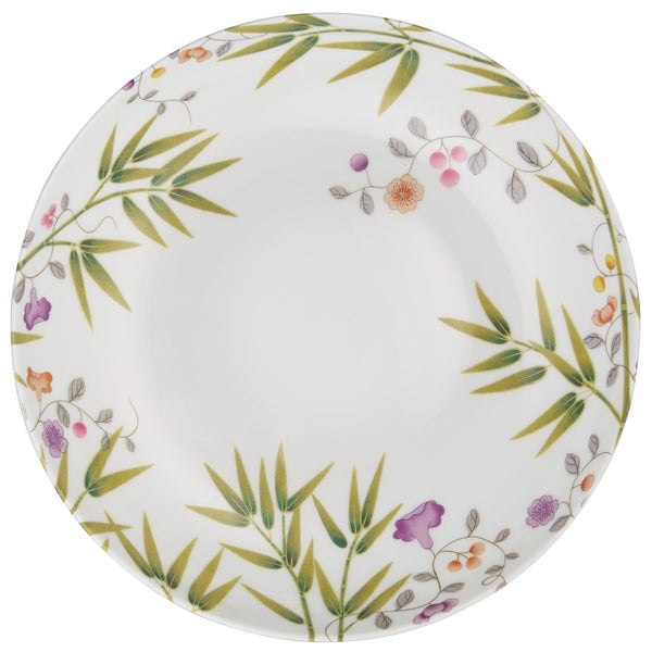 A white porcelain deep plate with green and brown floral patterns.