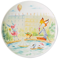 A colorful porcelain dessert plate from Raynaud featuring hand-painted characters including hares, mice, and a fox, with a background that includes the Eiffel Tower and Notre Dame Cathedral.