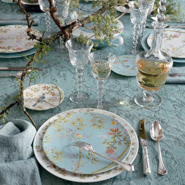dinner plates in blue with floral design on blue tablecloth with glasses