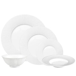 A set of white porcelain dinnerware, including plates and bowls, with a counter-relief engraving pattern.