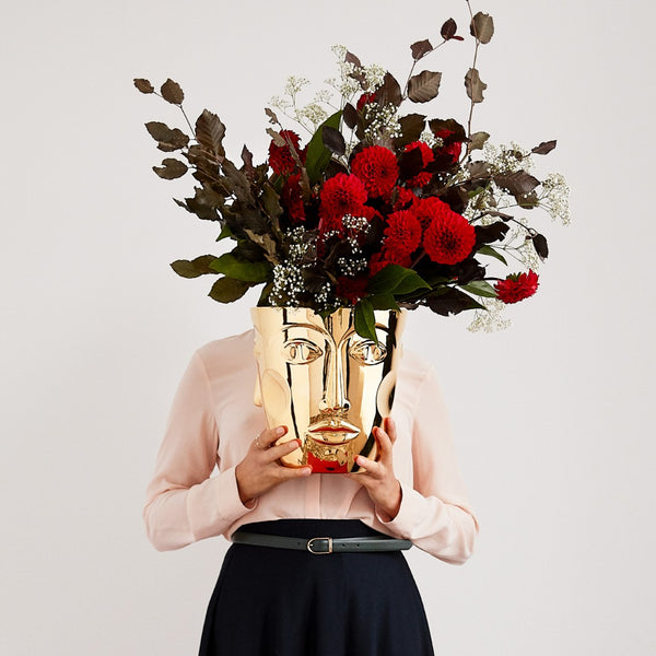 woman holding a gold vase with flowers