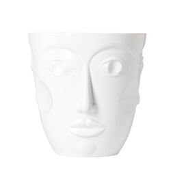 A white glazed porcelain vase with three relief-carved feminine faces on a plain background.