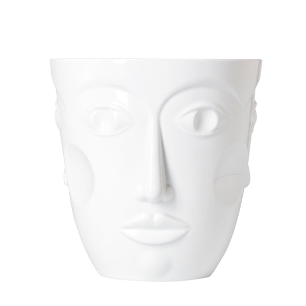 A white glazed porcelain vase with three relief-carved feminine faces on a plain background.