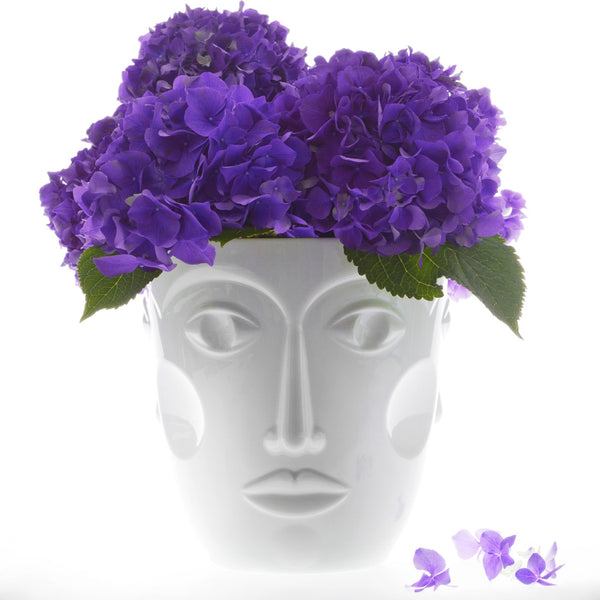 white vase featuring a womans face with purple flowers