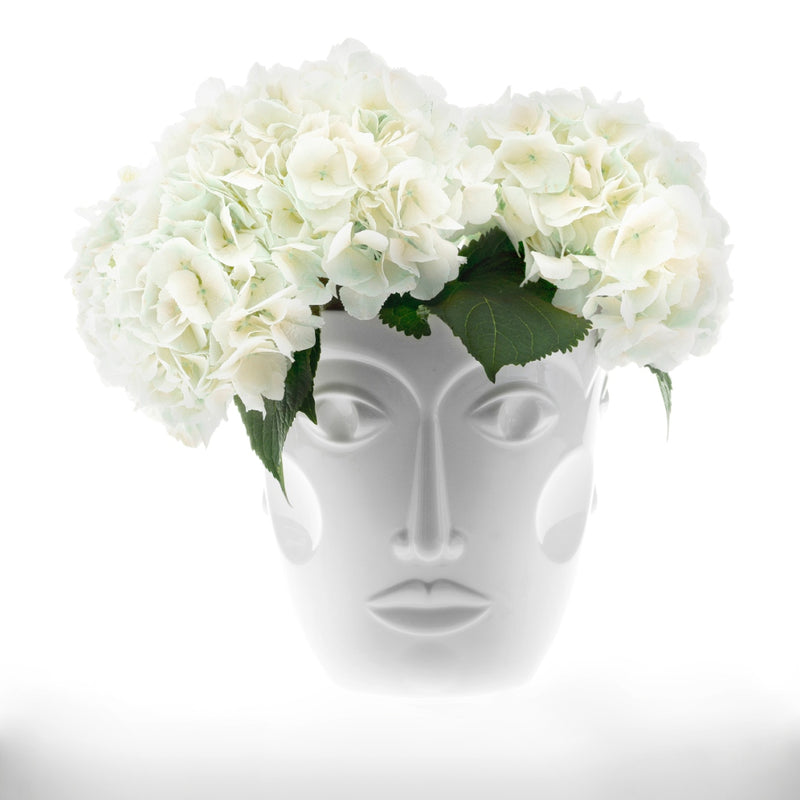 white vase featuring a womans face with white flowers