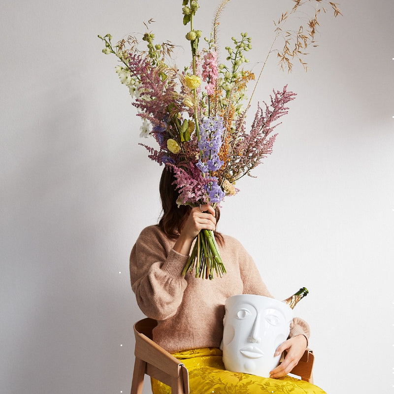 woman holding a bouquet of flowers and holding a white champagne cooler 